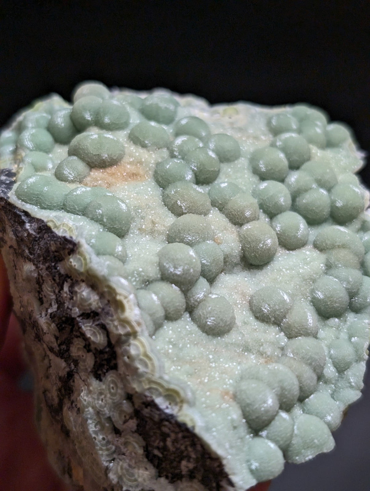 A pale green, spherical mineral specimen with a crystalline texture and earthy base.