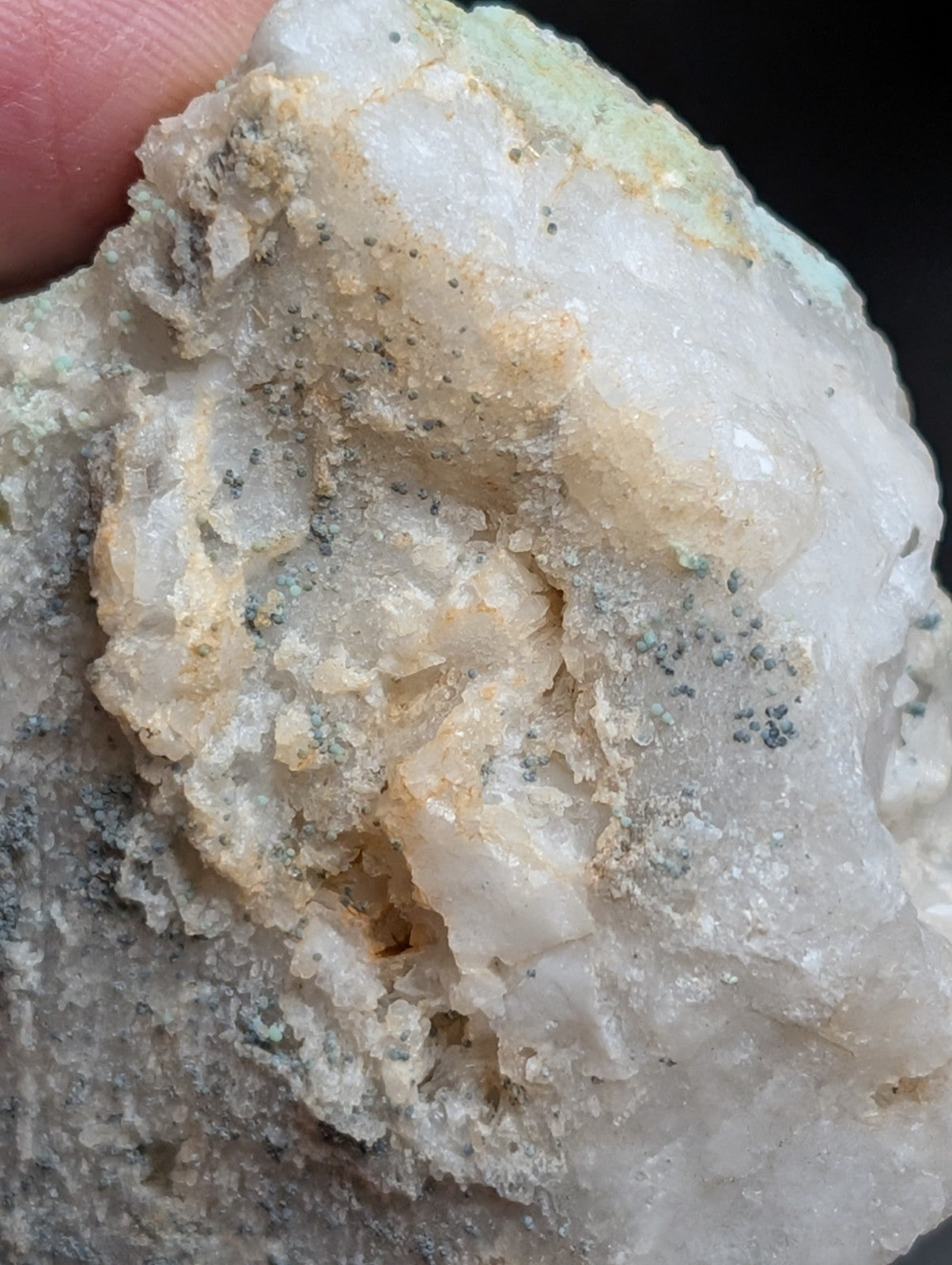 A rough, translucent white mineral specimen with patches of greenish and yellowish veining.