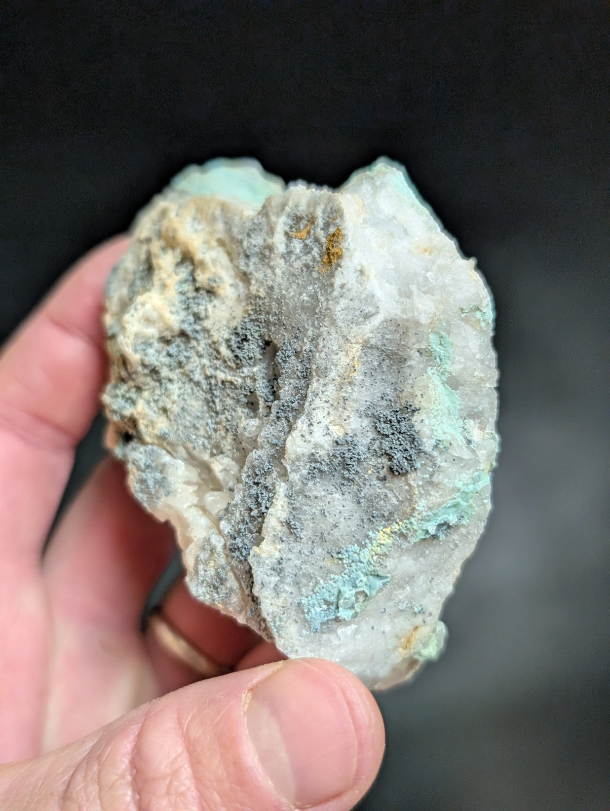 A rough, irregularly shaped mineral specimen with a mix of white crystalline areas and patches of greenish-blue patina.