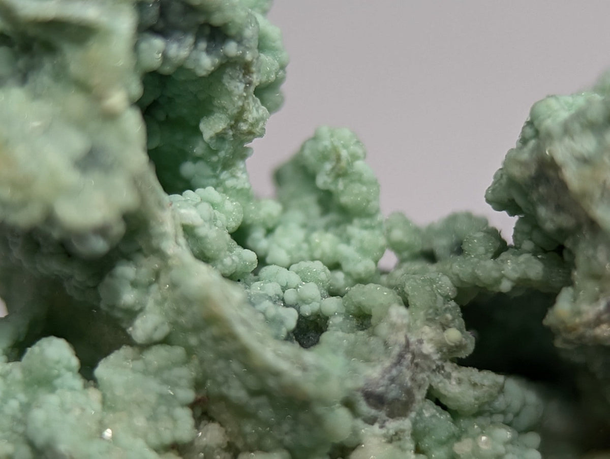 A textured, light green mineral specimen with a crystalline, bumpy surface.