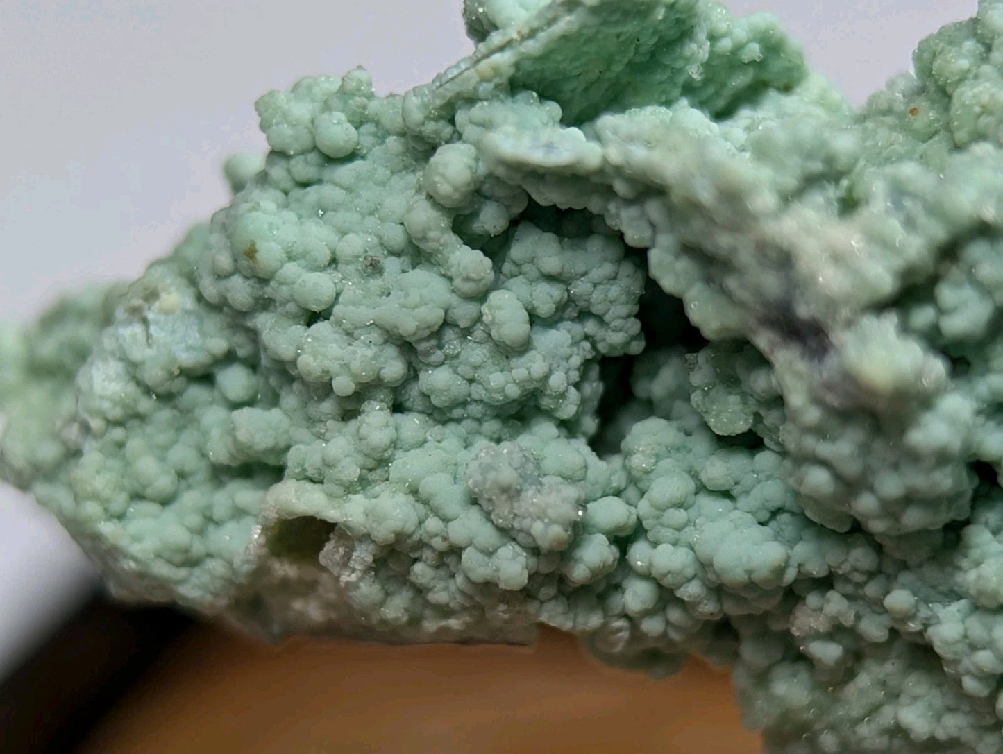 A textured, light green mineral specimen with a crystalline, bubbly surface.