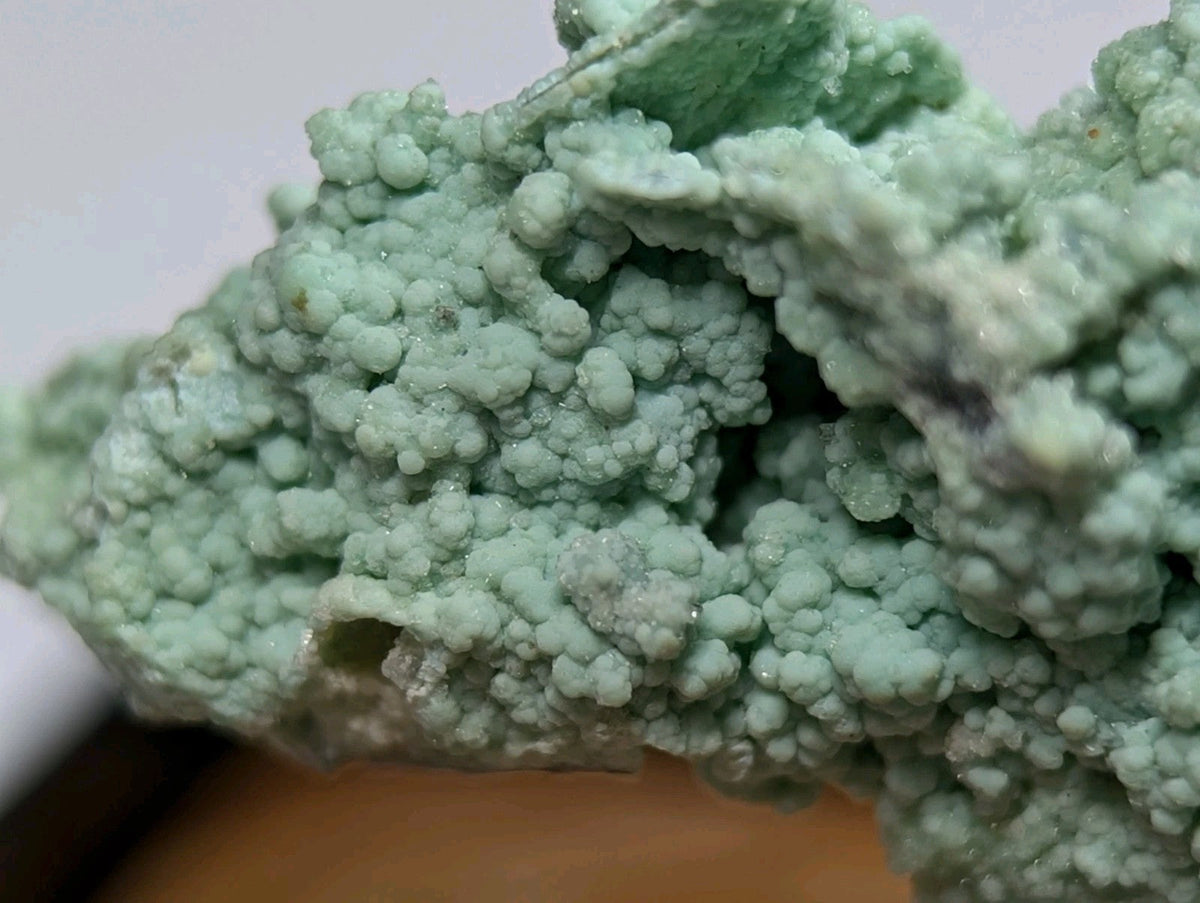 A textured, light green mineral specimen with a crystalline, bubbly surface.