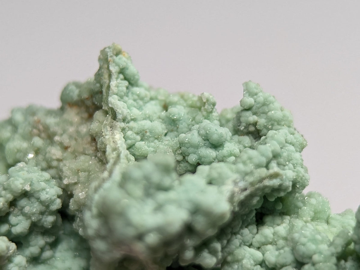 A cluster of pale green, crystalline minerals with a rough, textured surface.
