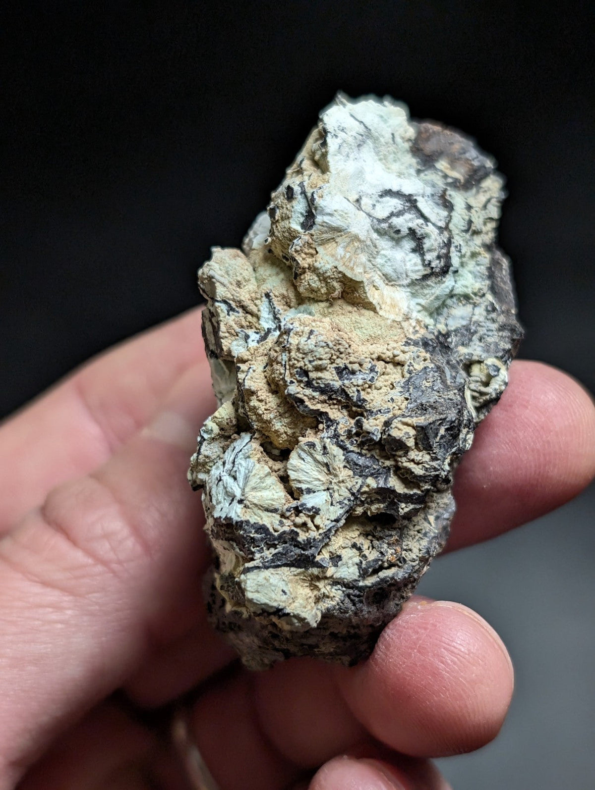 A rugged, irregularly shaped mineral specimen with a mottled surface of greenish-blue and beige hues, featuring visible crystalline textures.