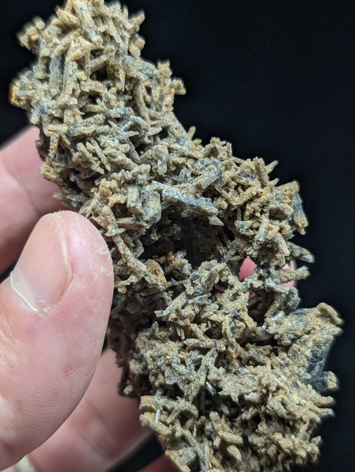 A dense cluster of earthy brown and grayish crystalline formations with intricate, needle-like structures.