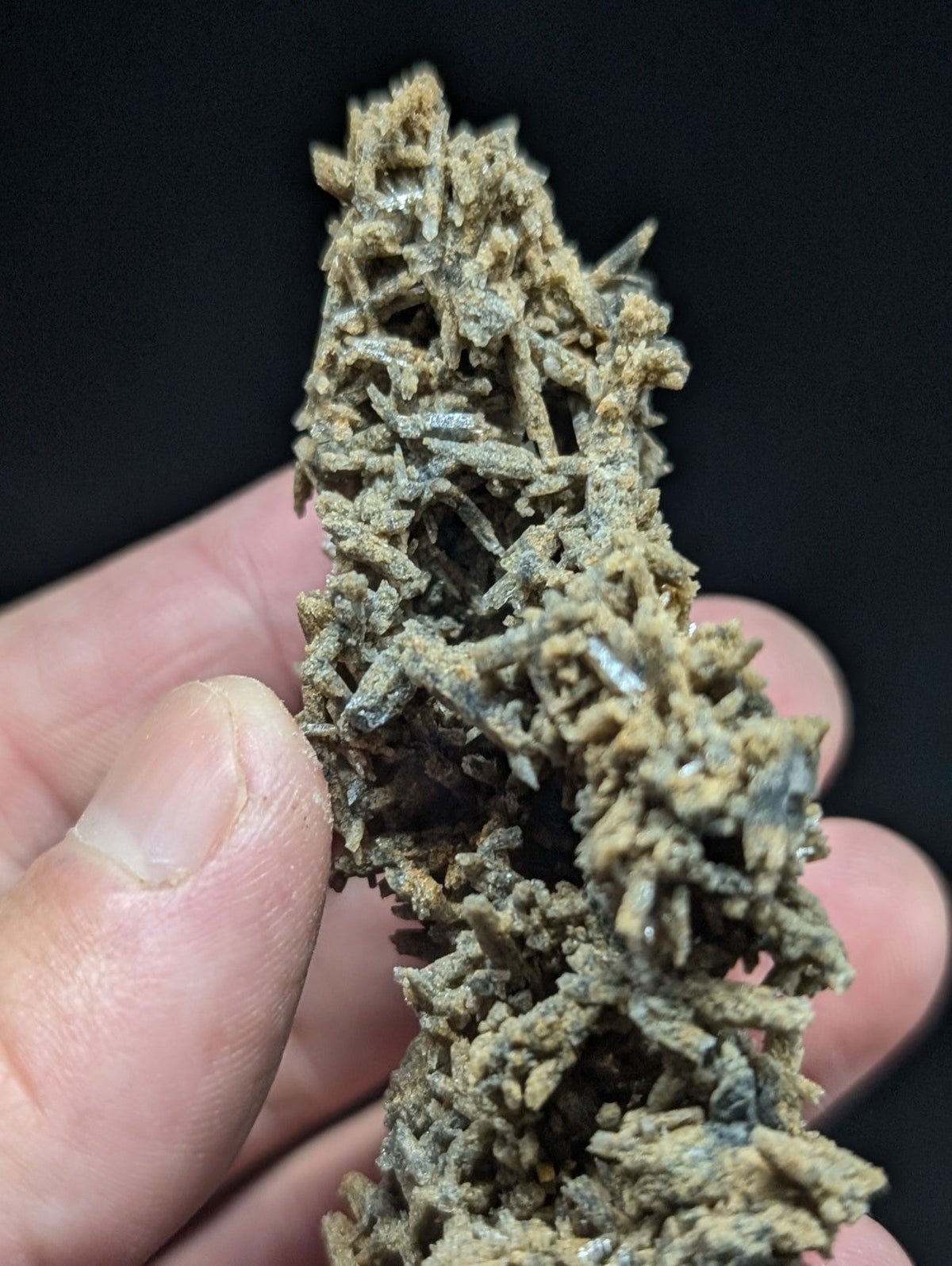 A textured, earthy-toned mineral specimen with a complex lattice of intergrown crystals.