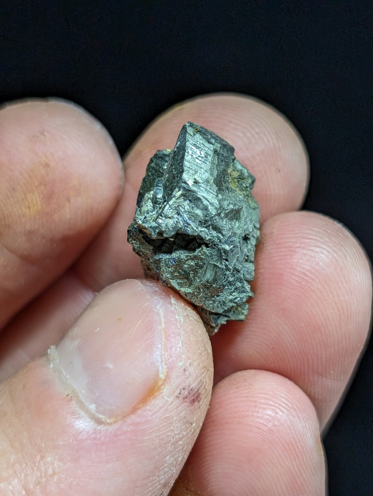 A rough, irregularly shaped mineral specimen with a metallic sheen and greenish patina.