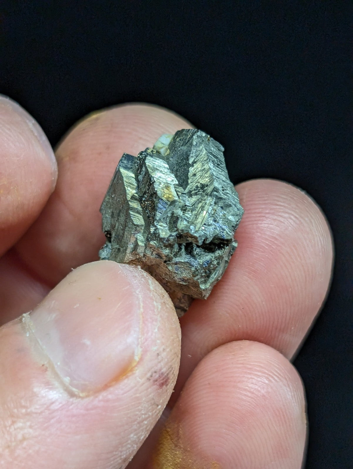 A rough, metallic green mineral specimen with visible crystalline facets and a slightly iridescent sheen.