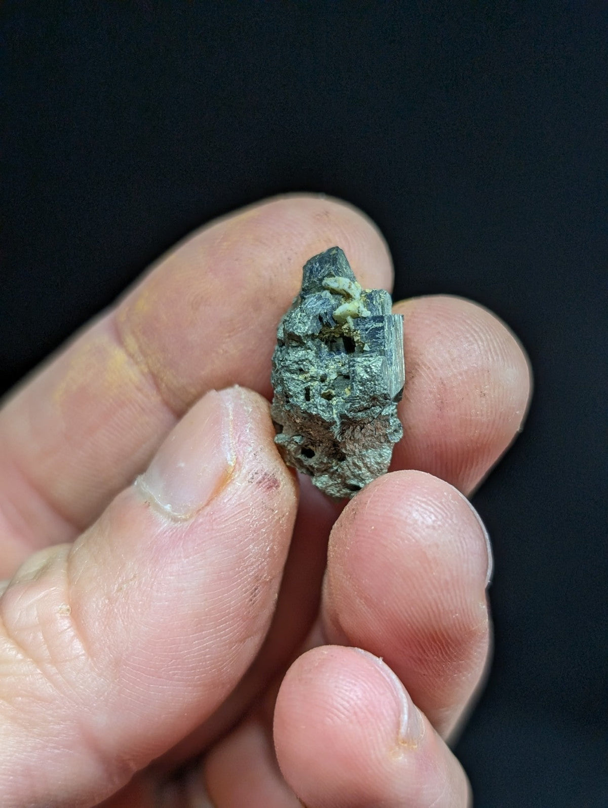 A weathered, greenish-blue mineral specimen with a rough, textured surface and visible crystalline facets.