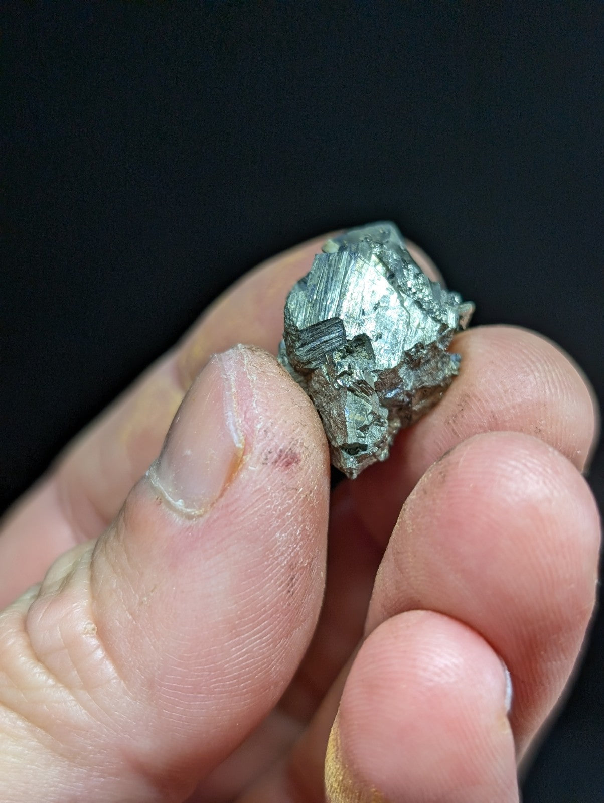 A rough, metallic greenish-gray mineral specimen with a crystalline structure.