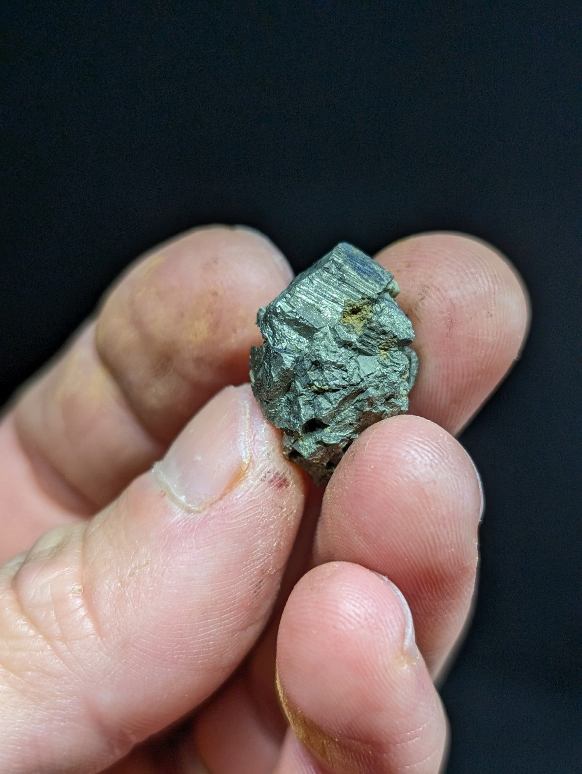 A rough, greenish-blue mineral specimen with visible crystalline facets and a slightly weathered surface.