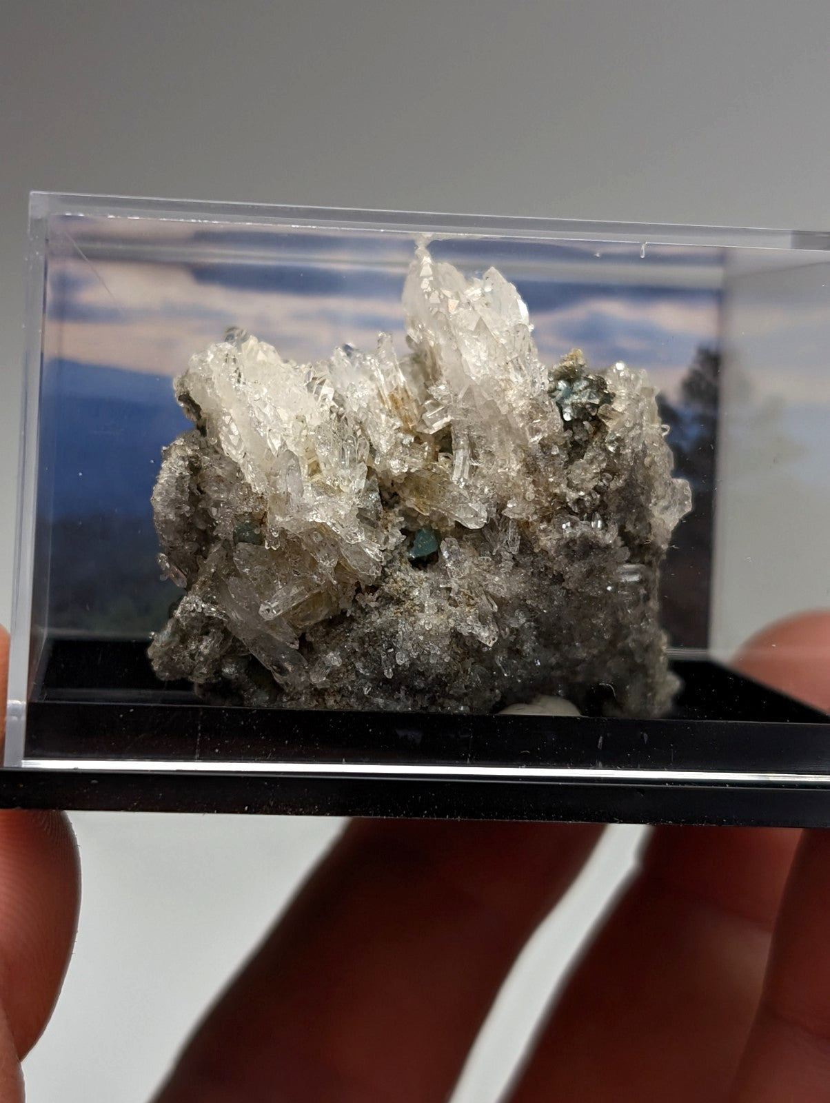 Quartz crystal cluster with blue-green cookeite in translucent gray tones displayed in a clear acrylic case from Arkansas