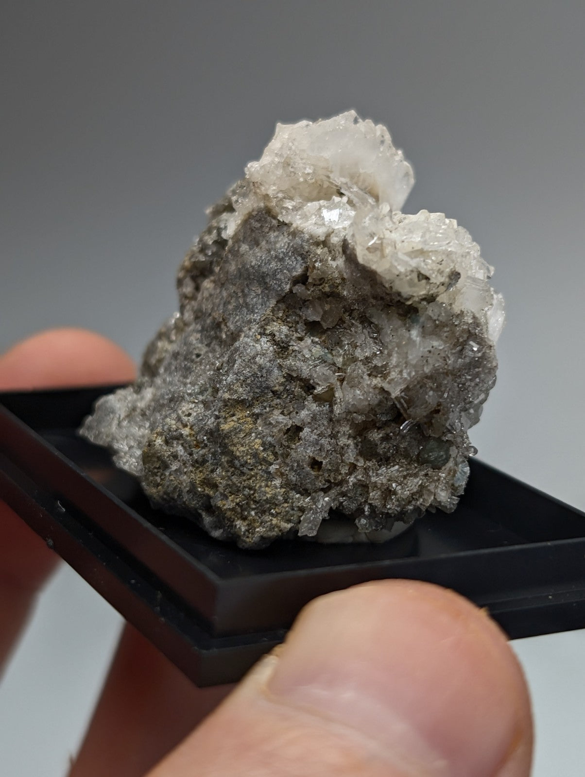 Quartz crystal cluster with blue-green cookeite on grayish mineral base from saline county Arkansas under UV light