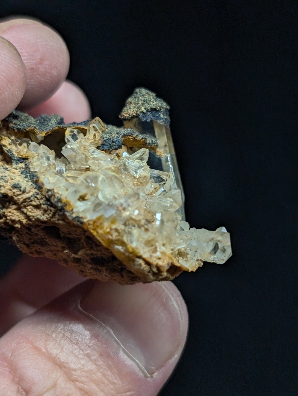 A translucent, crystalline quartz cluster with a rough, earthy matrix of brown and gray hues.