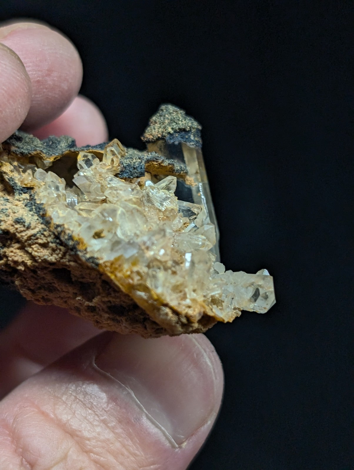 A translucent, crystalline quartz cluster with a rough, earthy matrix of brown and gray hues.