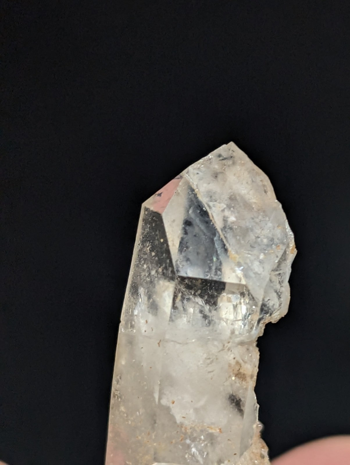 A translucent, clear quartz crystal with a pointed tip and natural facets.