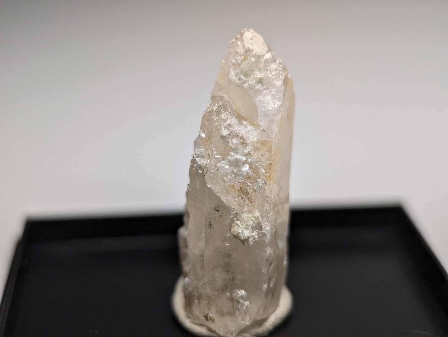 A translucent clear quartz crystal point with natural mineral inclusions on a circular base from Arkansas USA