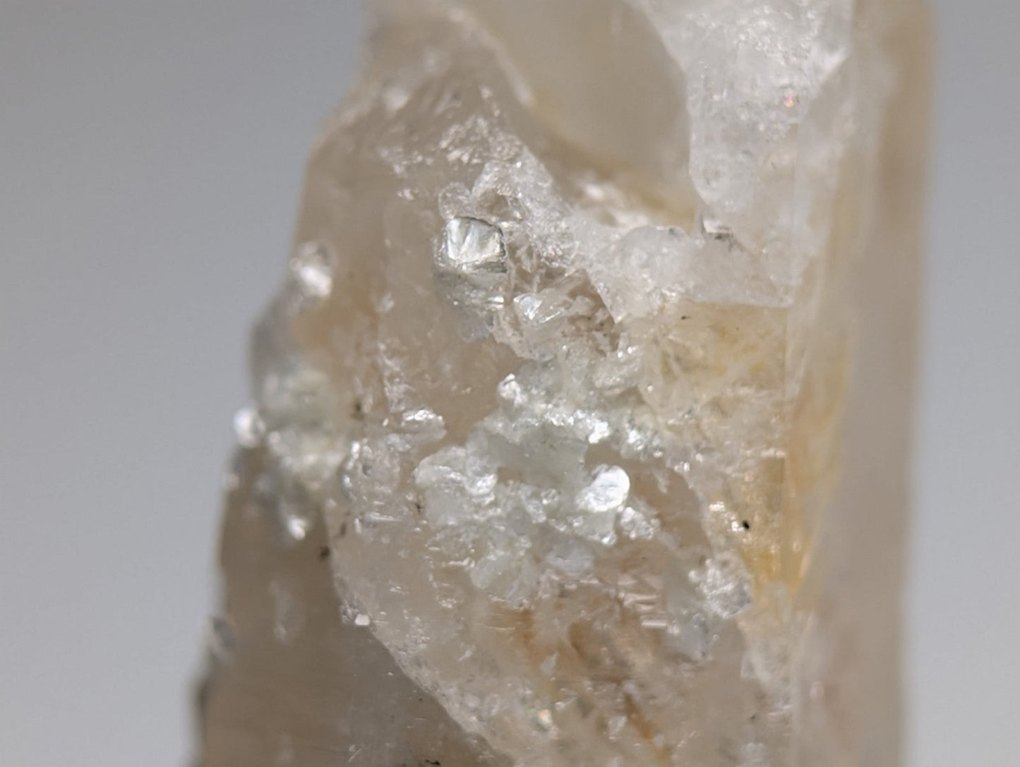 Quartz crystal point with uv reactive cookeite showing pale yellow translucent quartz and clear mineral inclusions