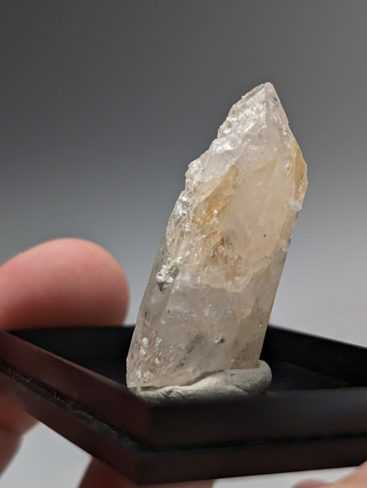 A translucent pale yellow quartz crystal point with rough surface and uv reactive cookeite from saline county Arkansas