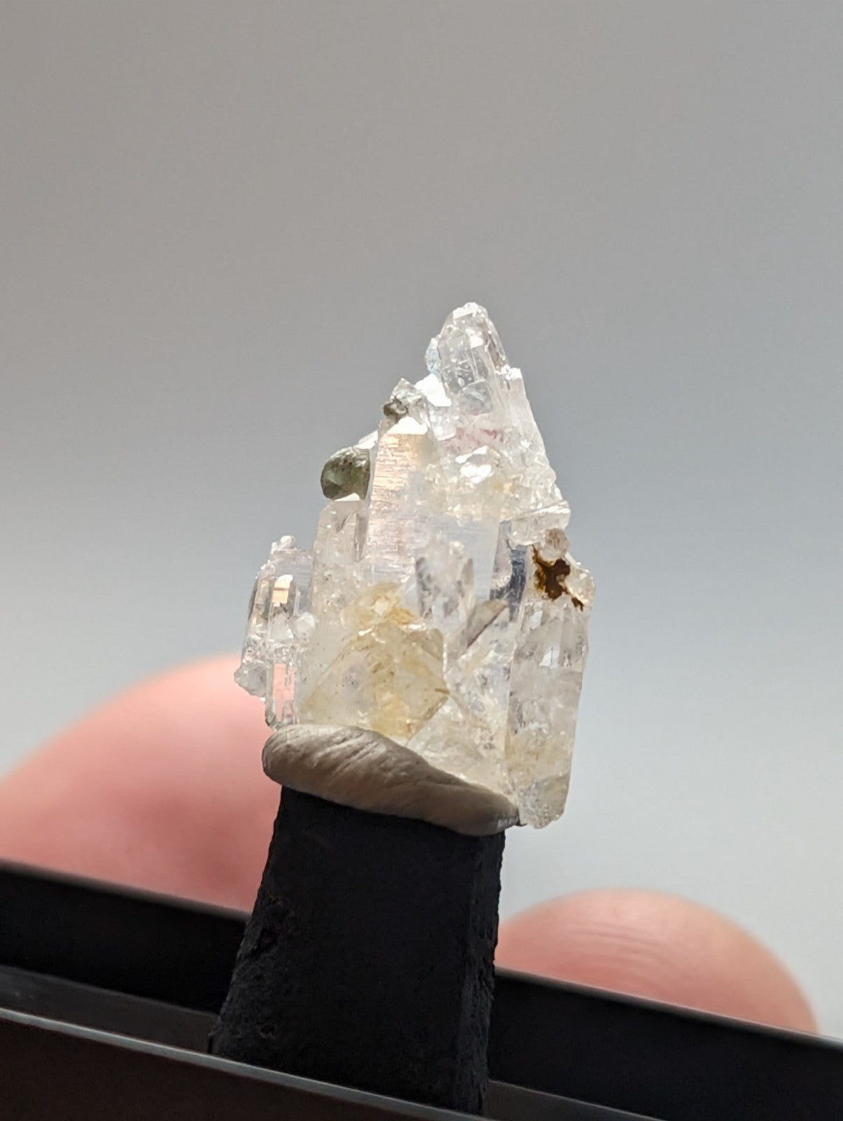 A translucent, crystalline mineral specimen with clear and pale yellow facets mounted on a black display stand.
