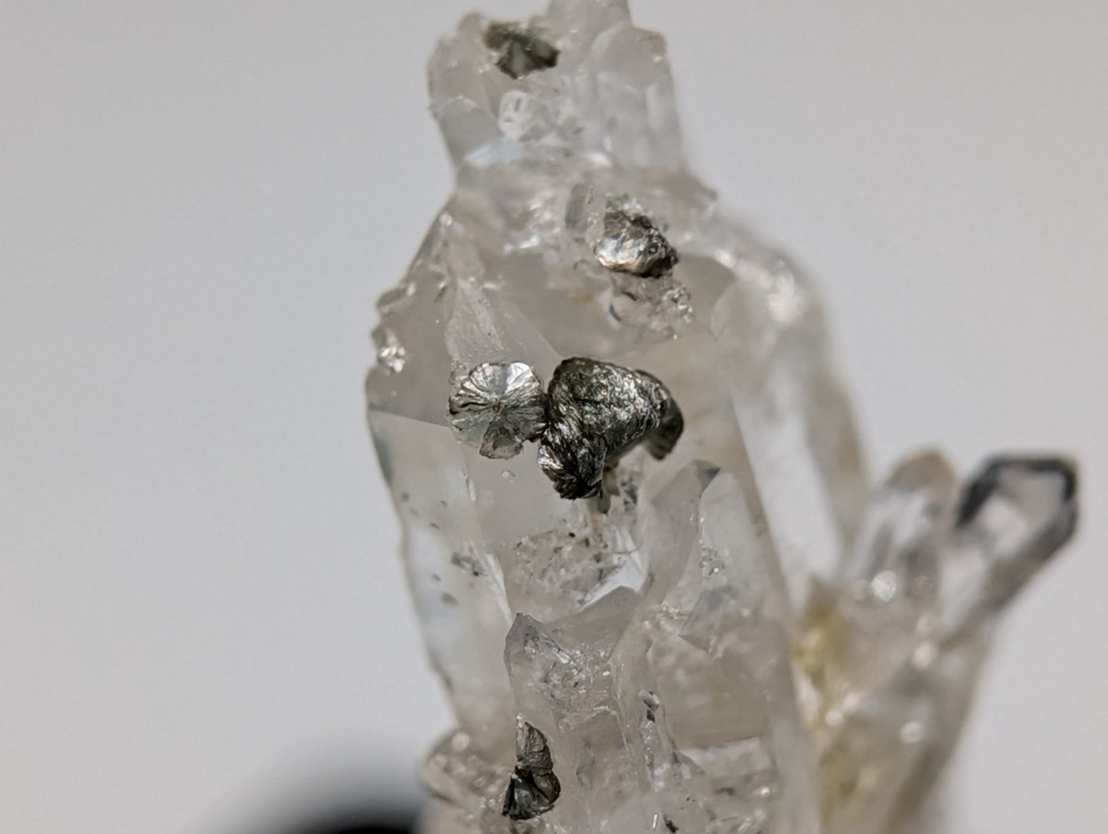 A translucent quartz crystal formation with embedded metallic silver inclusions.