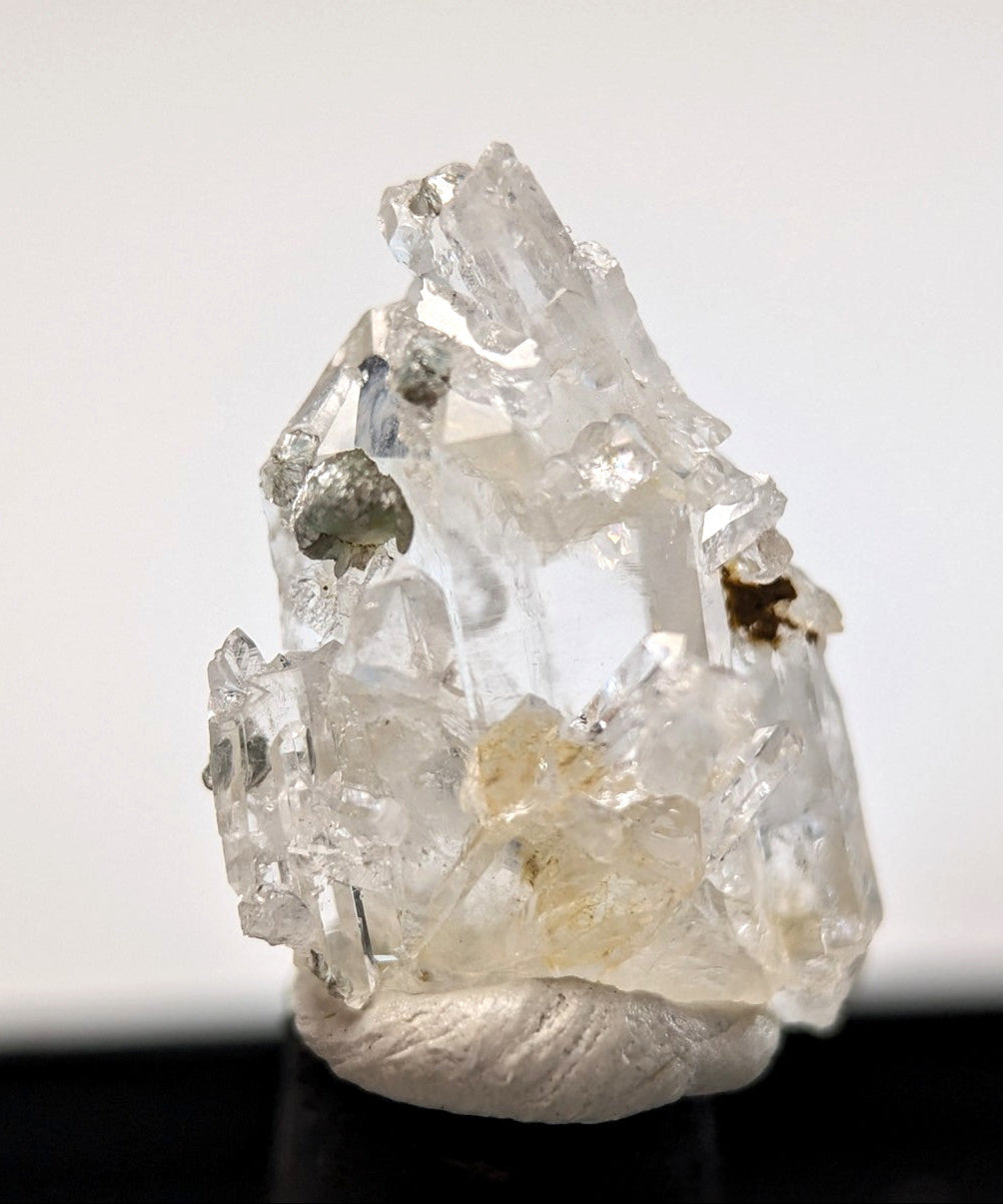 Clear quartz crystal cluster with translucent facets and embedded metallic inclusions.
