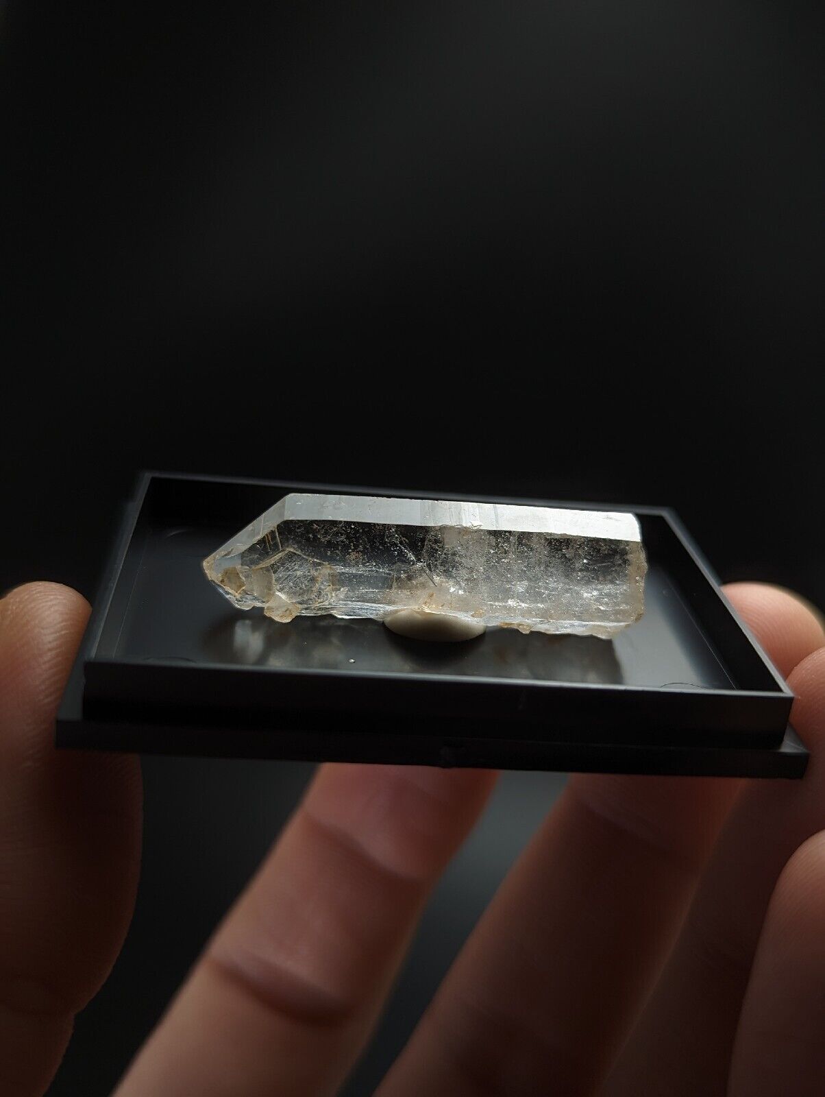 Translucent crystal specimen in a black display case.