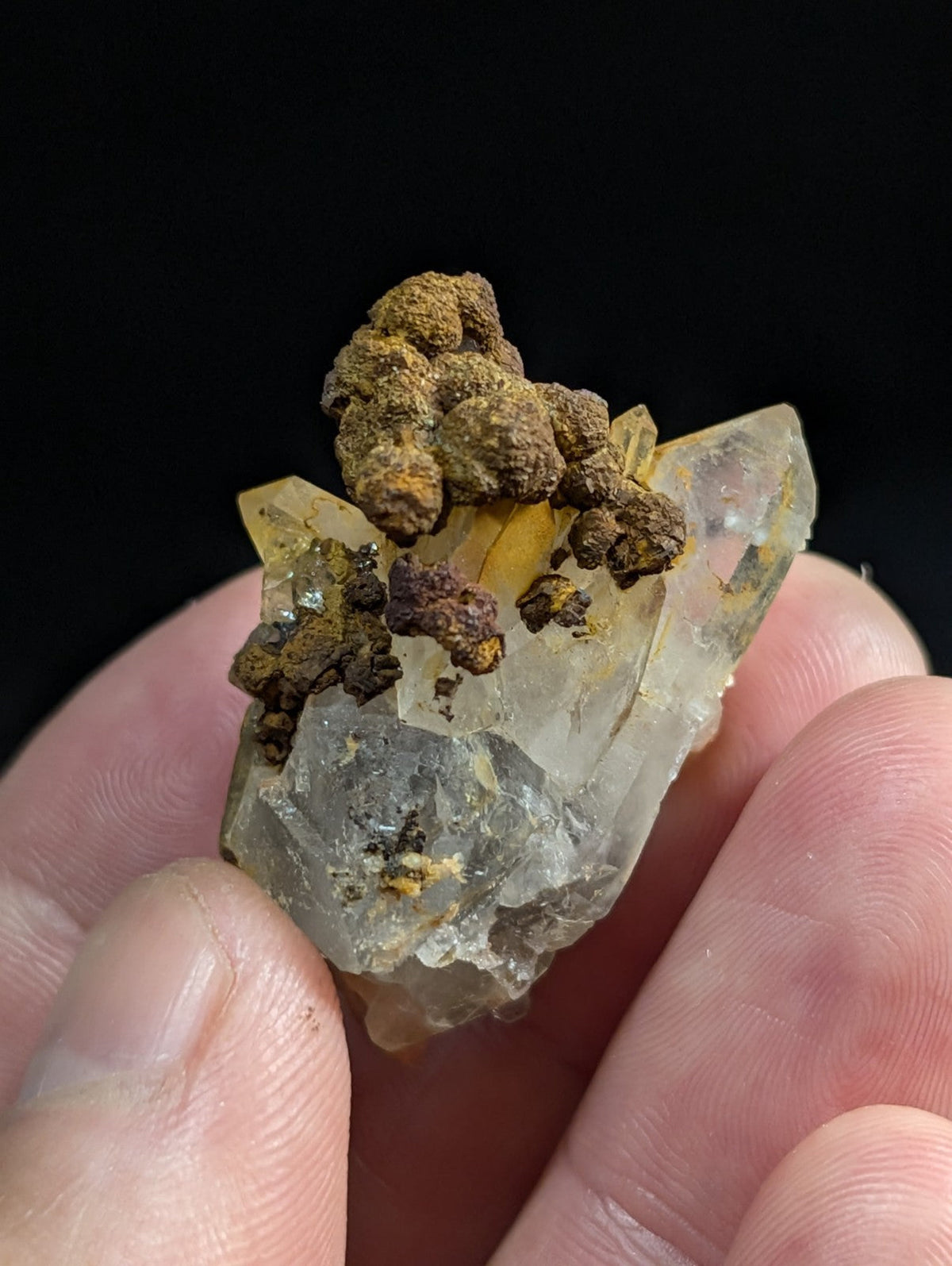 A translucent yellowish quartz crystal cluster with brown, earthy mineral formations on top.