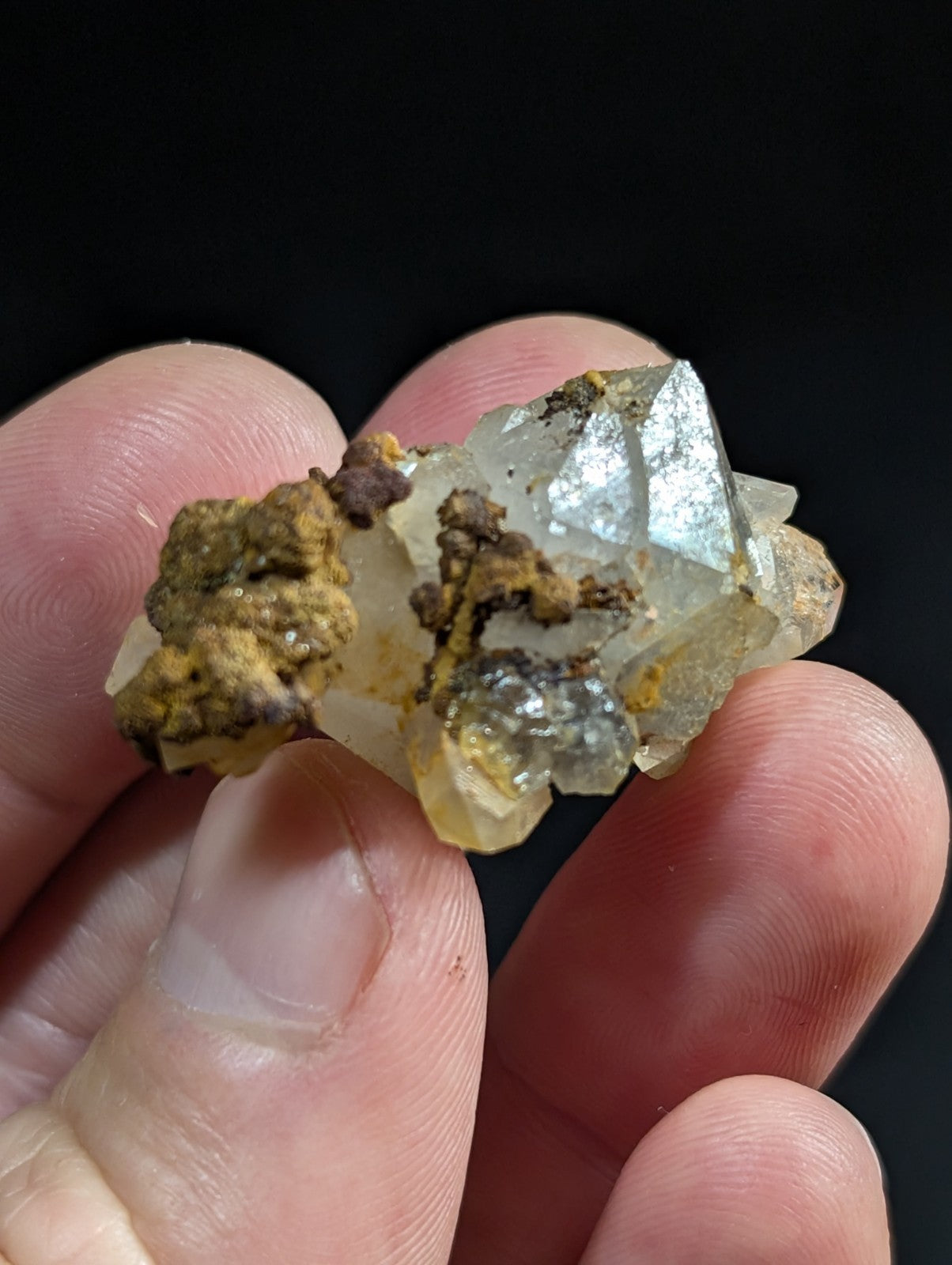 A translucent, crystalline mineral specimen with sharp facets and a mix of clear to pale yellow hues, accented by patches of brownish-yellow oxidation.