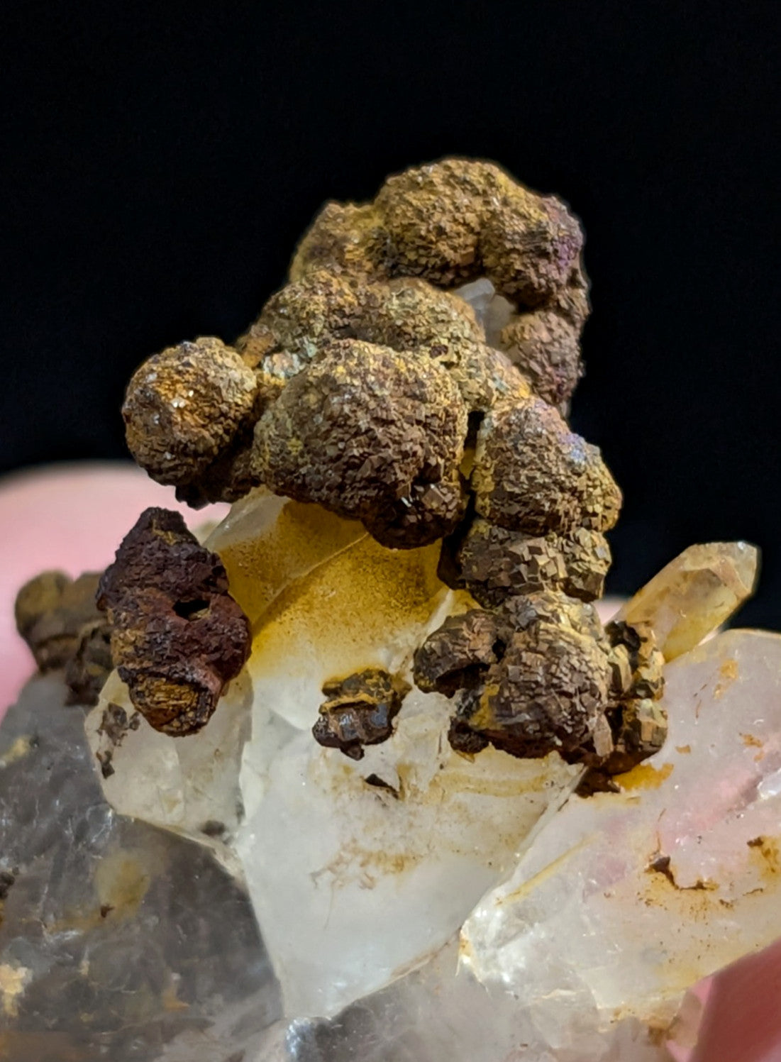 A rugged, earthy-brown mineral formation with a rough, clustered texture sits atop translucent quartz crystals.
