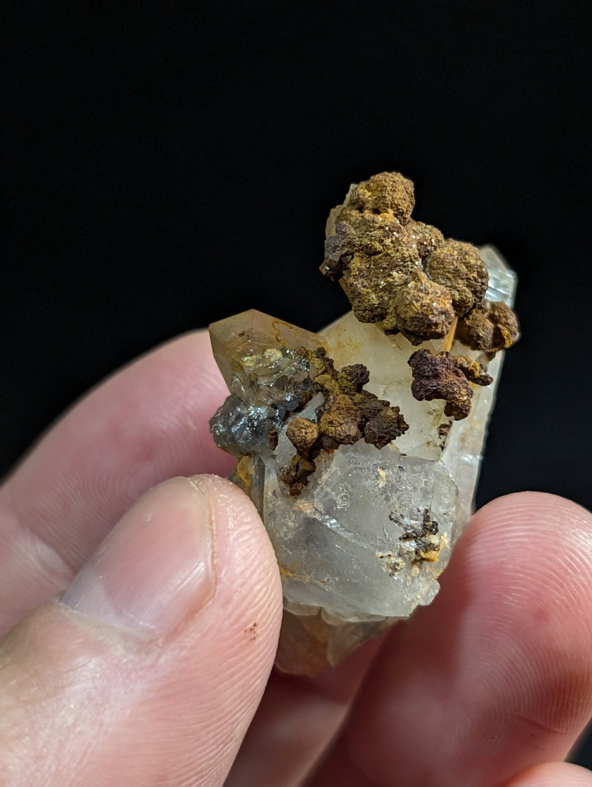 A translucent quartz crystal cluster with earthy brown and black mineral inclusions.
