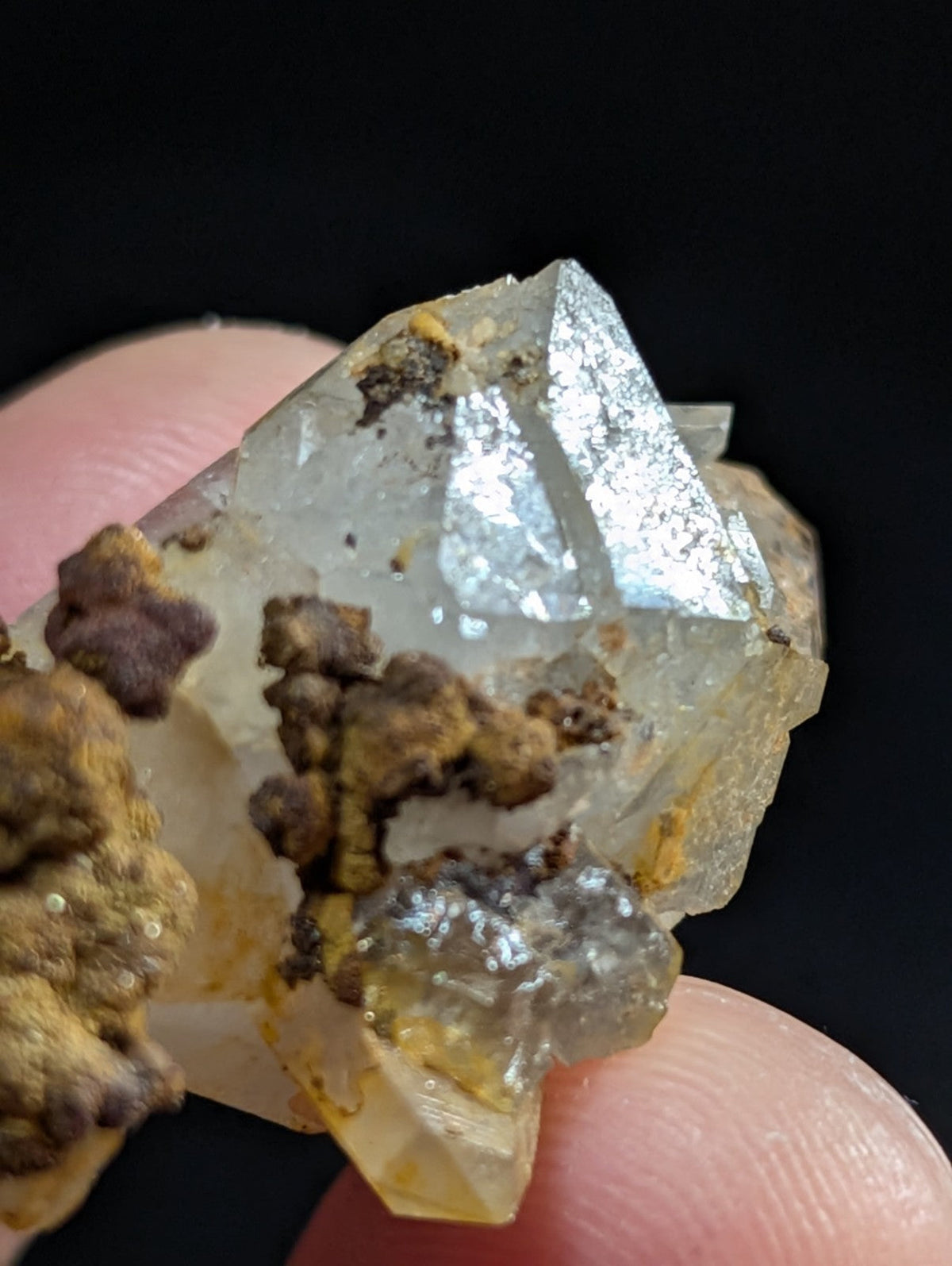 A translucent, faceted quartz crystal cluster with earthy brown and yellow mineral inclusions.