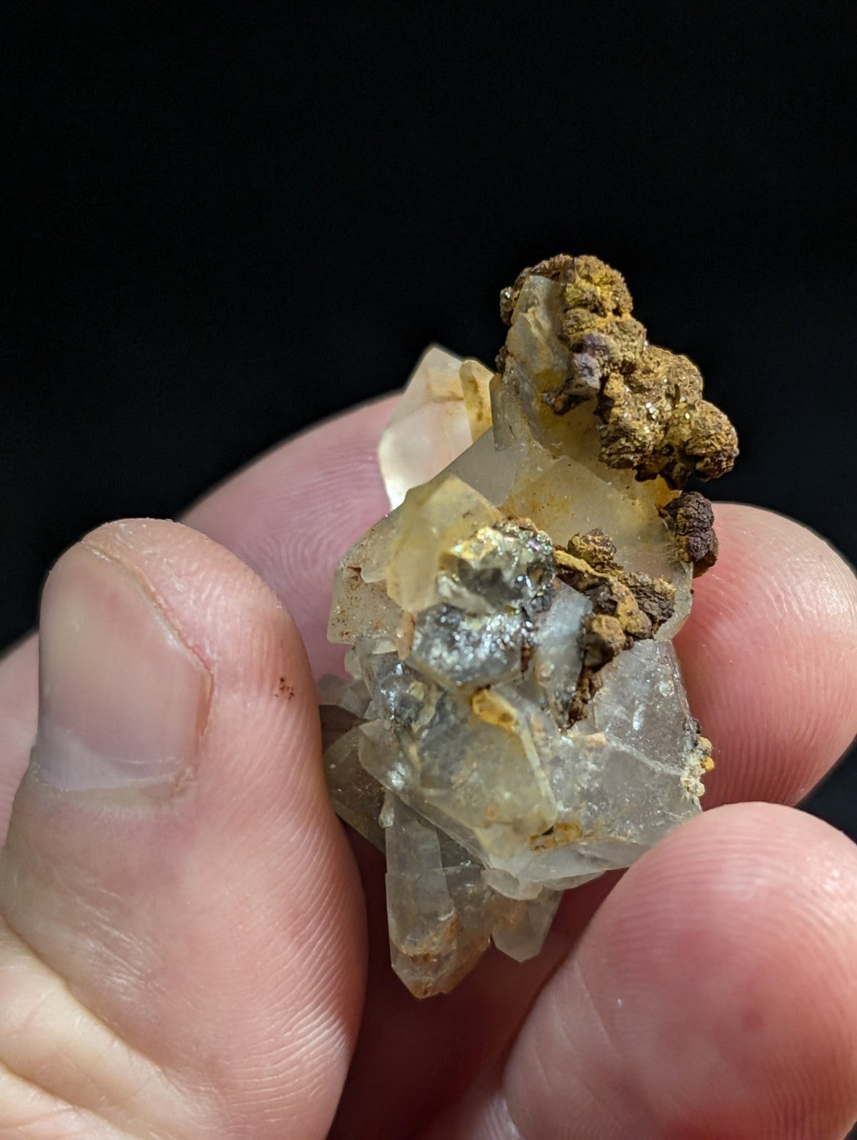 A translucent, crystalline mineral specimen with embedded metallic and earthy brown inclusions.