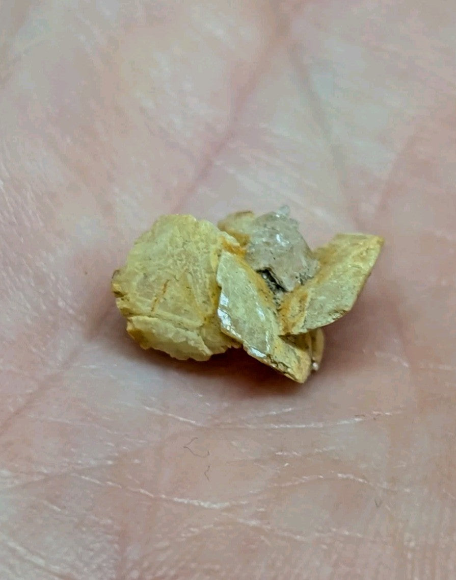A chunky, irregularly shaped piece of raw gold with a matte yellow surface and some shiny metallic facets.
