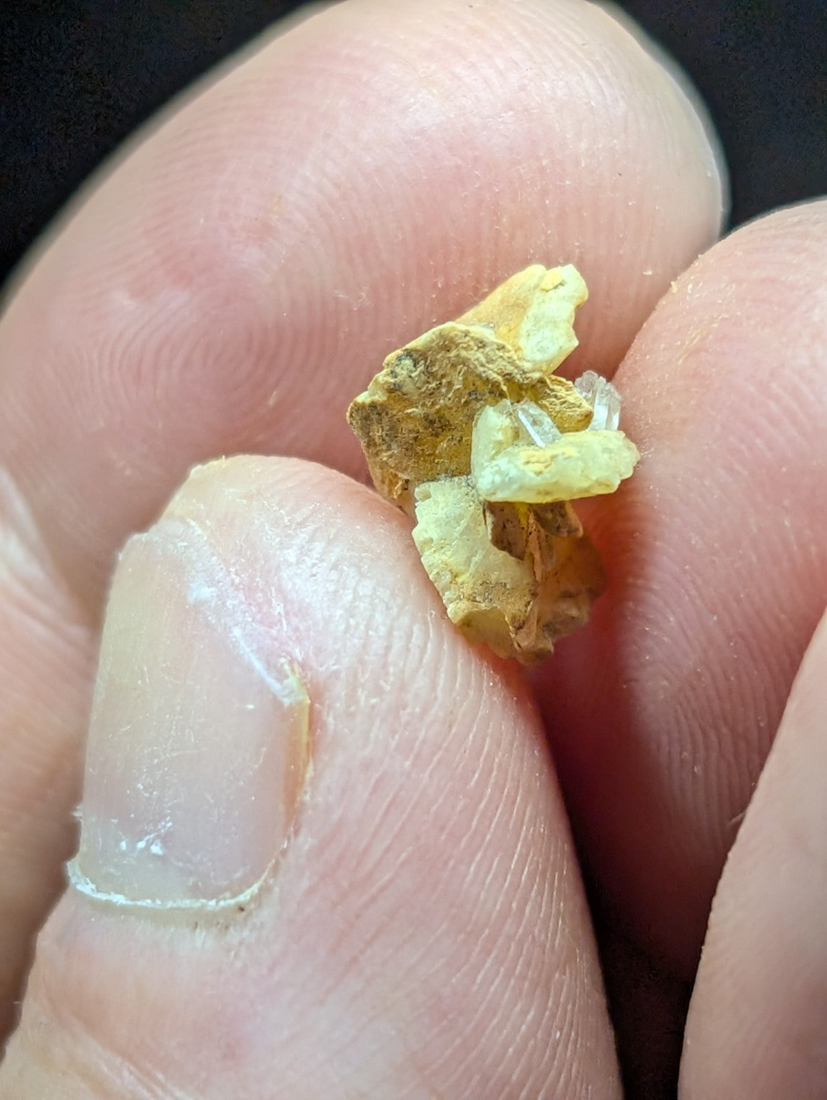 A small, irregularly shaped piece of yellowish mineral with translucent crystalline formations.