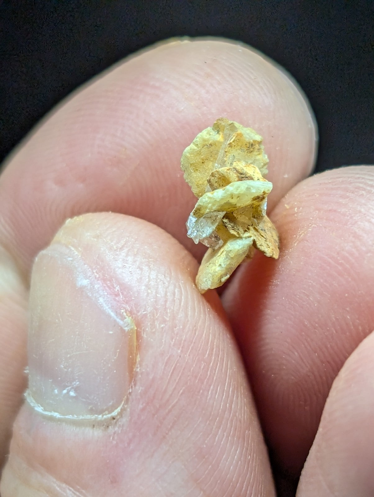 A small, irregularly shaped piece of raw gold with a rough, natural texture and patches of darker mineral residue.