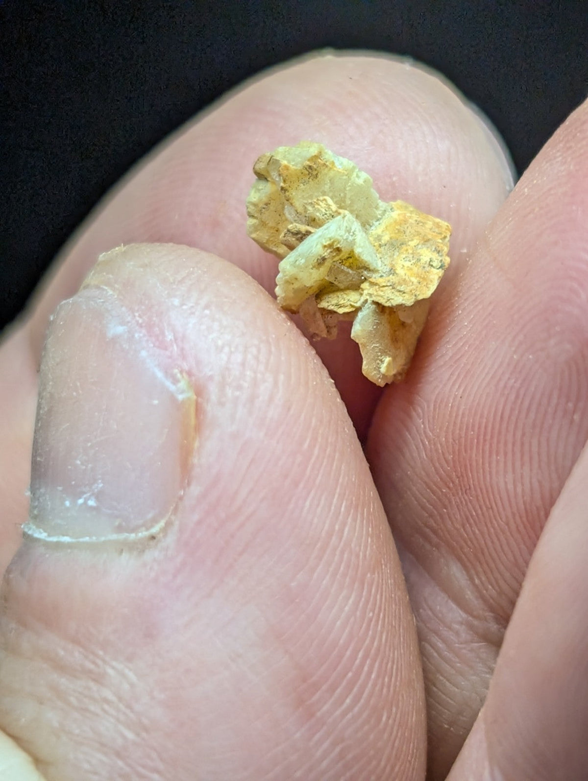 A small, irregularly shaped piece of raw gold with a rough, crystalline texture and a bright yellow hue.