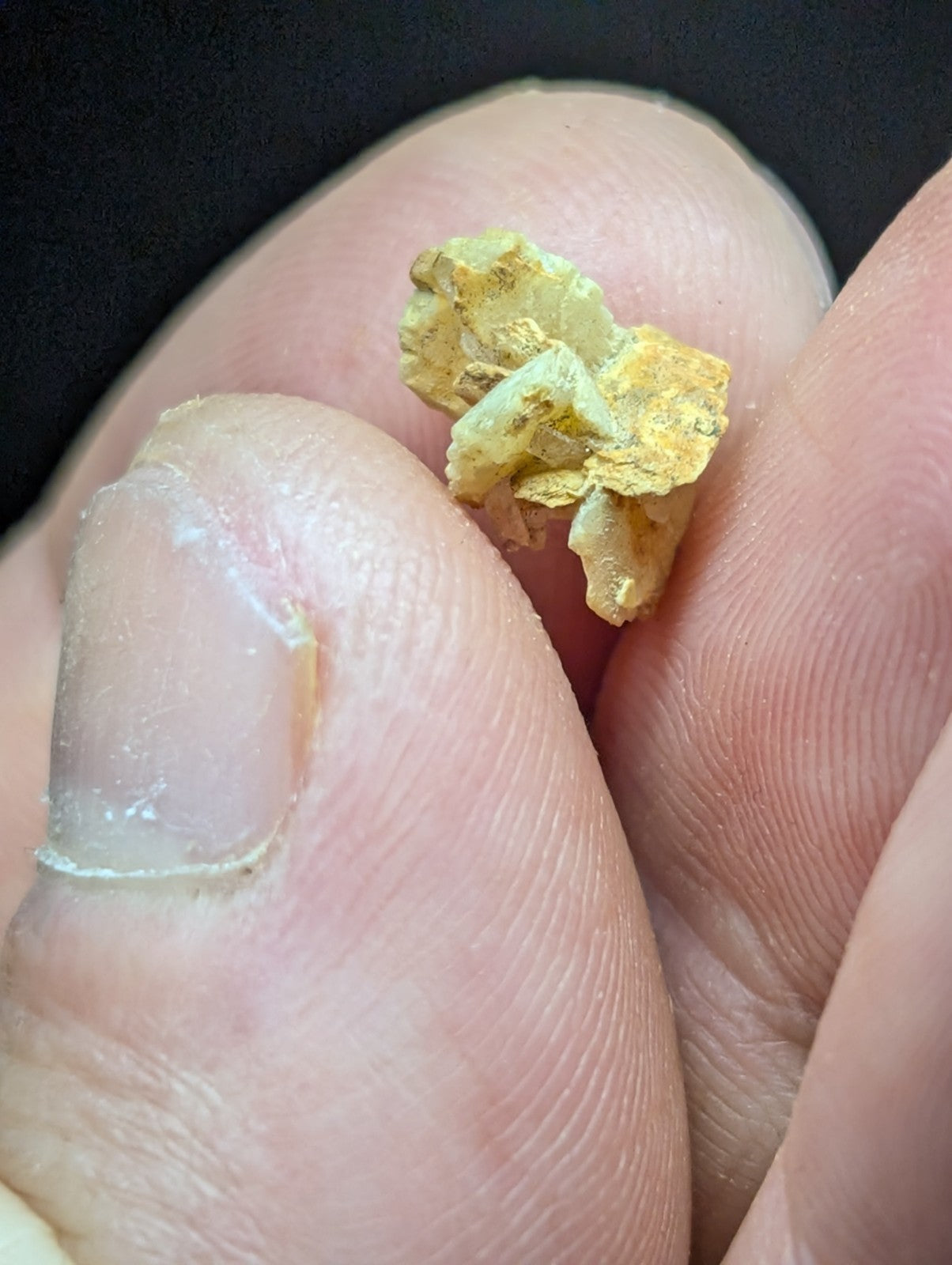 A small, irregularly shaped piece of raw gold with a rough, crystalline texture and a bright yellow hue.