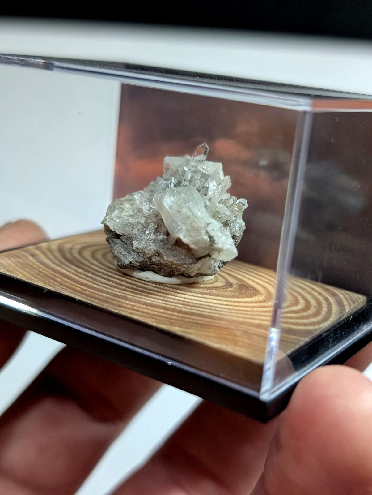 A translucent, crystalline mineral specimen with a grayish base and clear, faceted crystals growing from it.