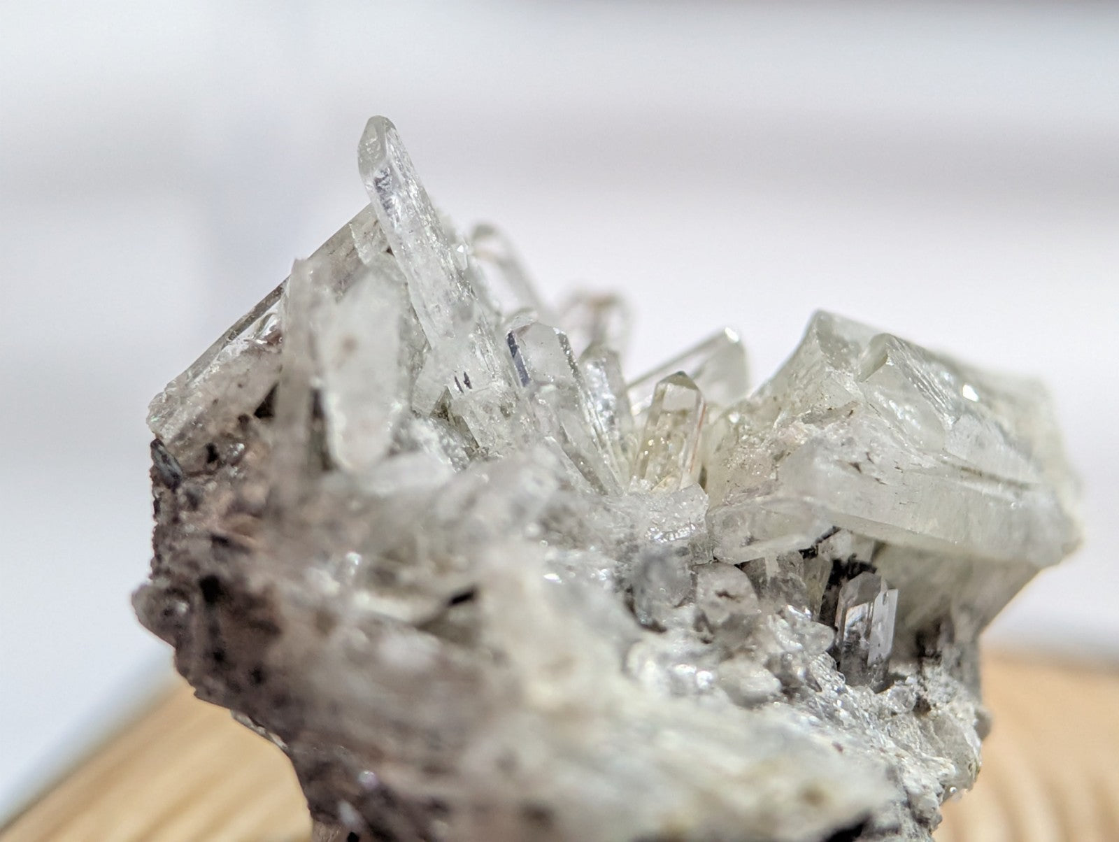 A translucent, crystalline mineral specimen with sharp, clear facets emerging from a rough, grayish rock base.