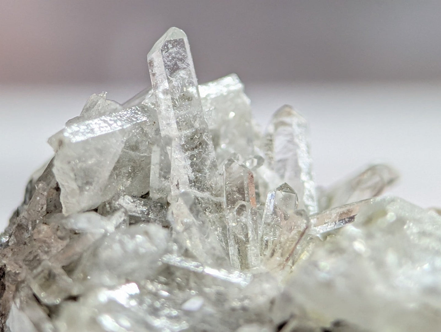 A cluster of transparent, faceted quartz crystals with sharp, pointed tips and a crystalline structure.