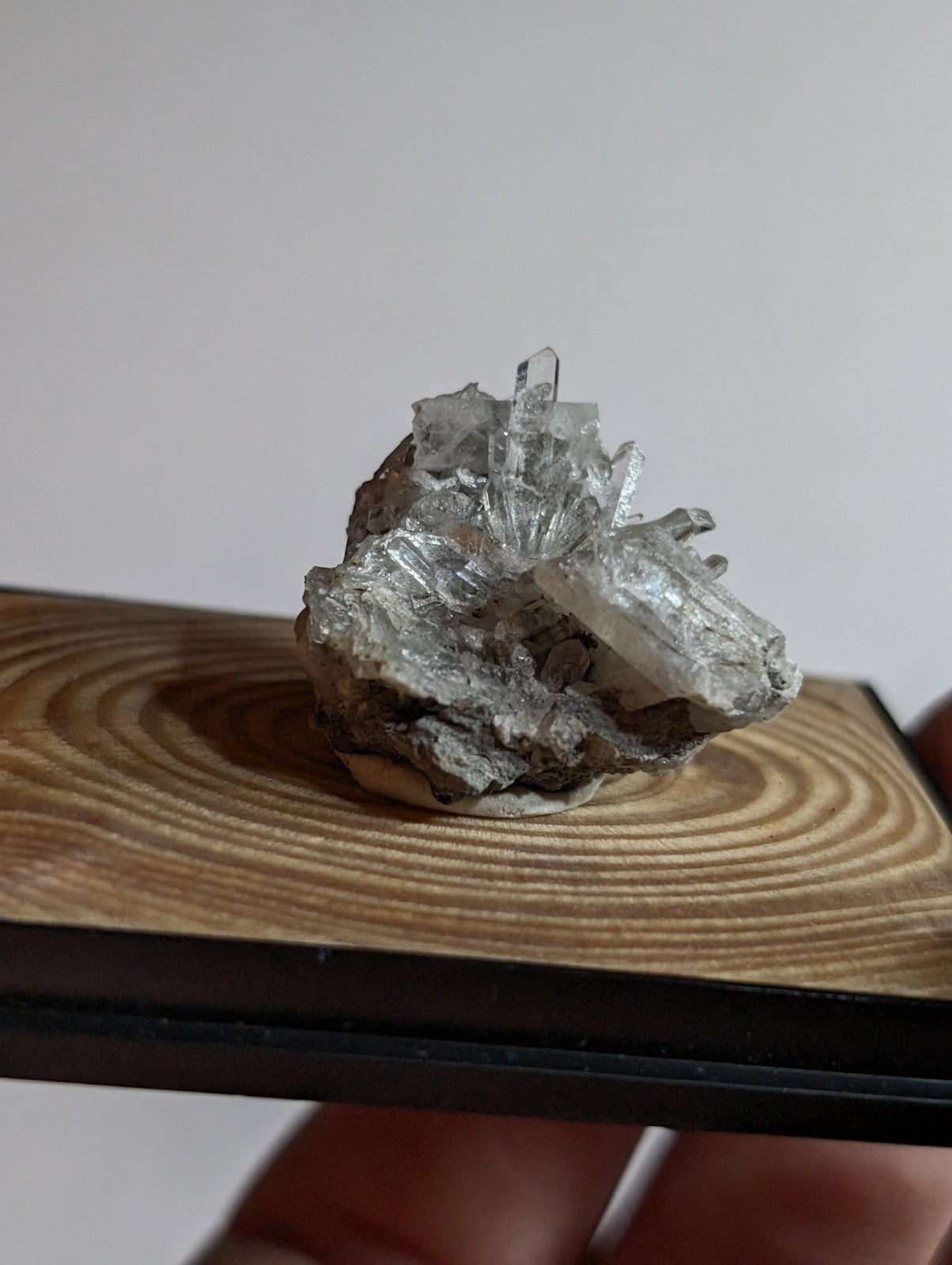 A clear, translucent quartz crystal cluster with sharp facets and a rough, grayish matrix base.