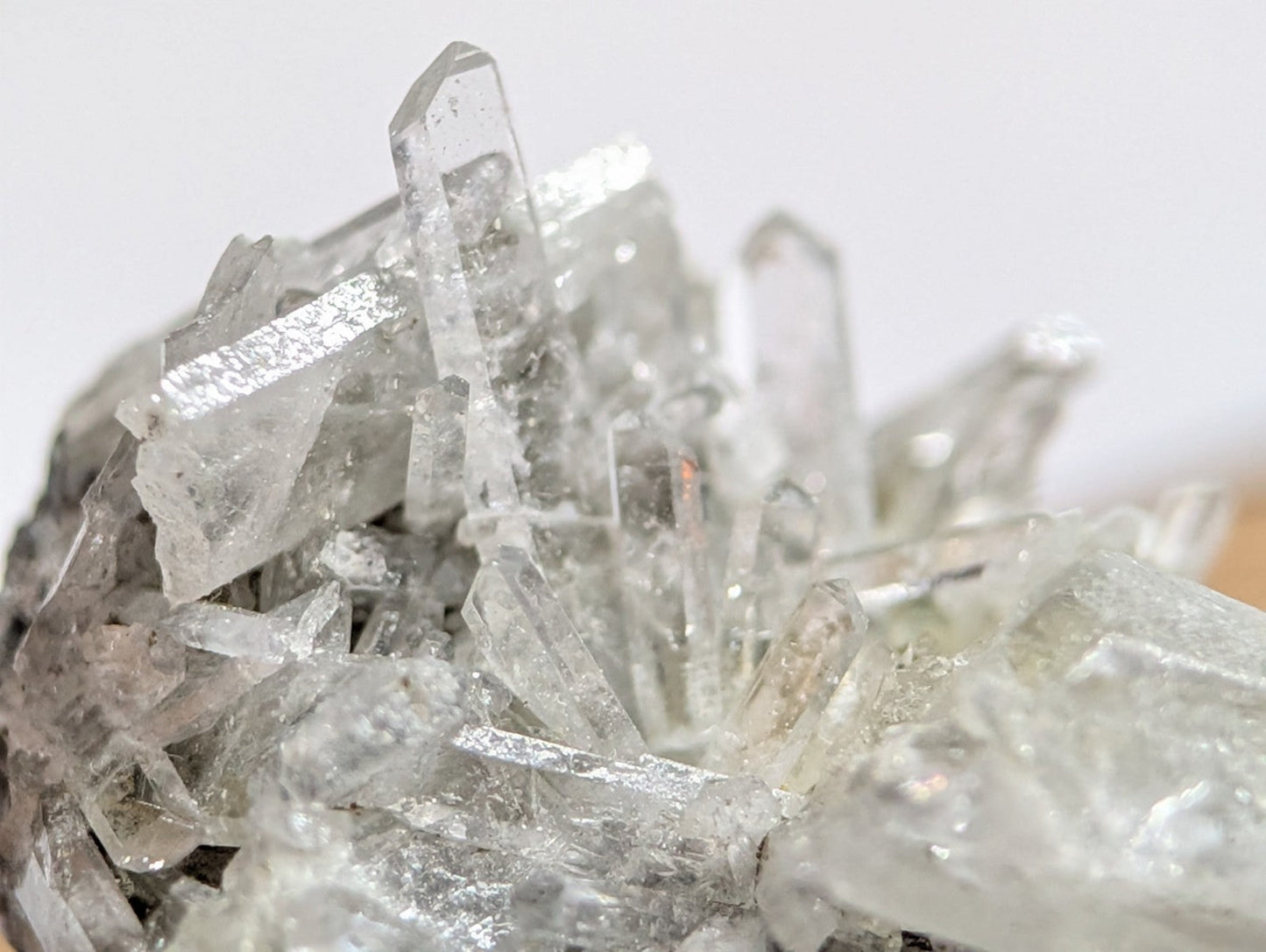 A cluster of clear, translucent quartz crystals with sharp, angular facets and a natural, earthy base.