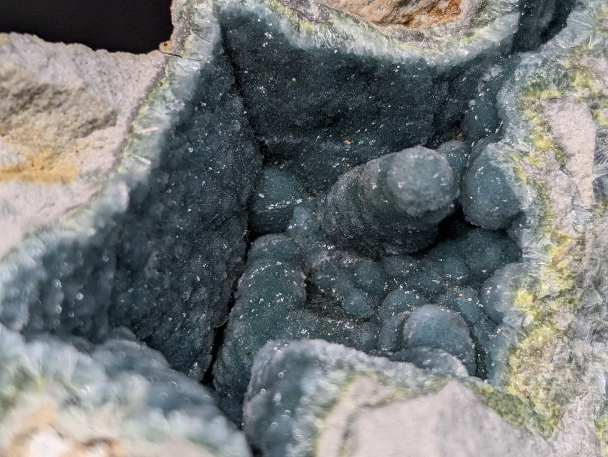 Dark green, rough-textured mineral formations nestled within a rocky cavity.