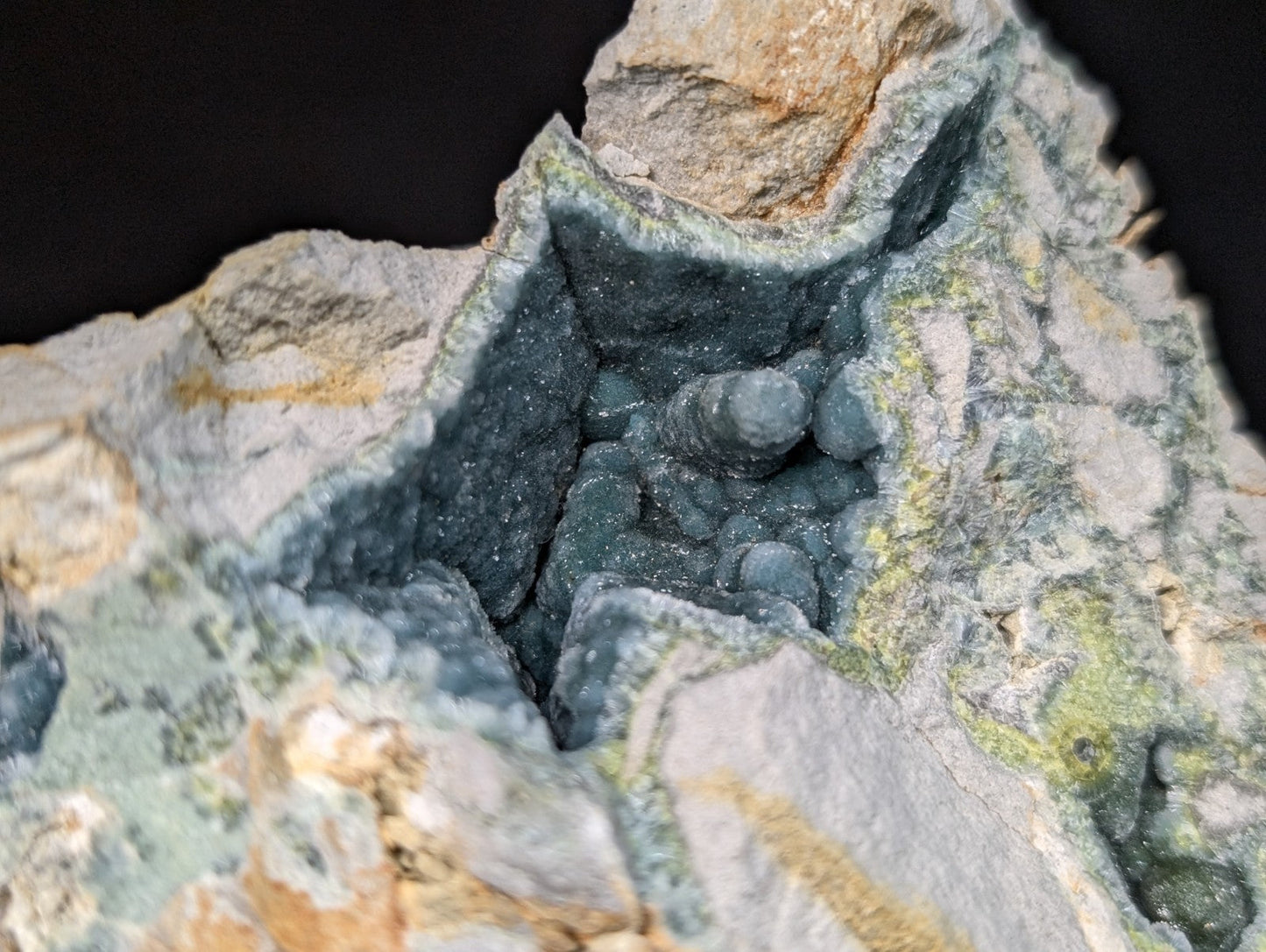 A striking greenish-blue mineral specimen with a rough, textured surface and embedded rounded nodules.
