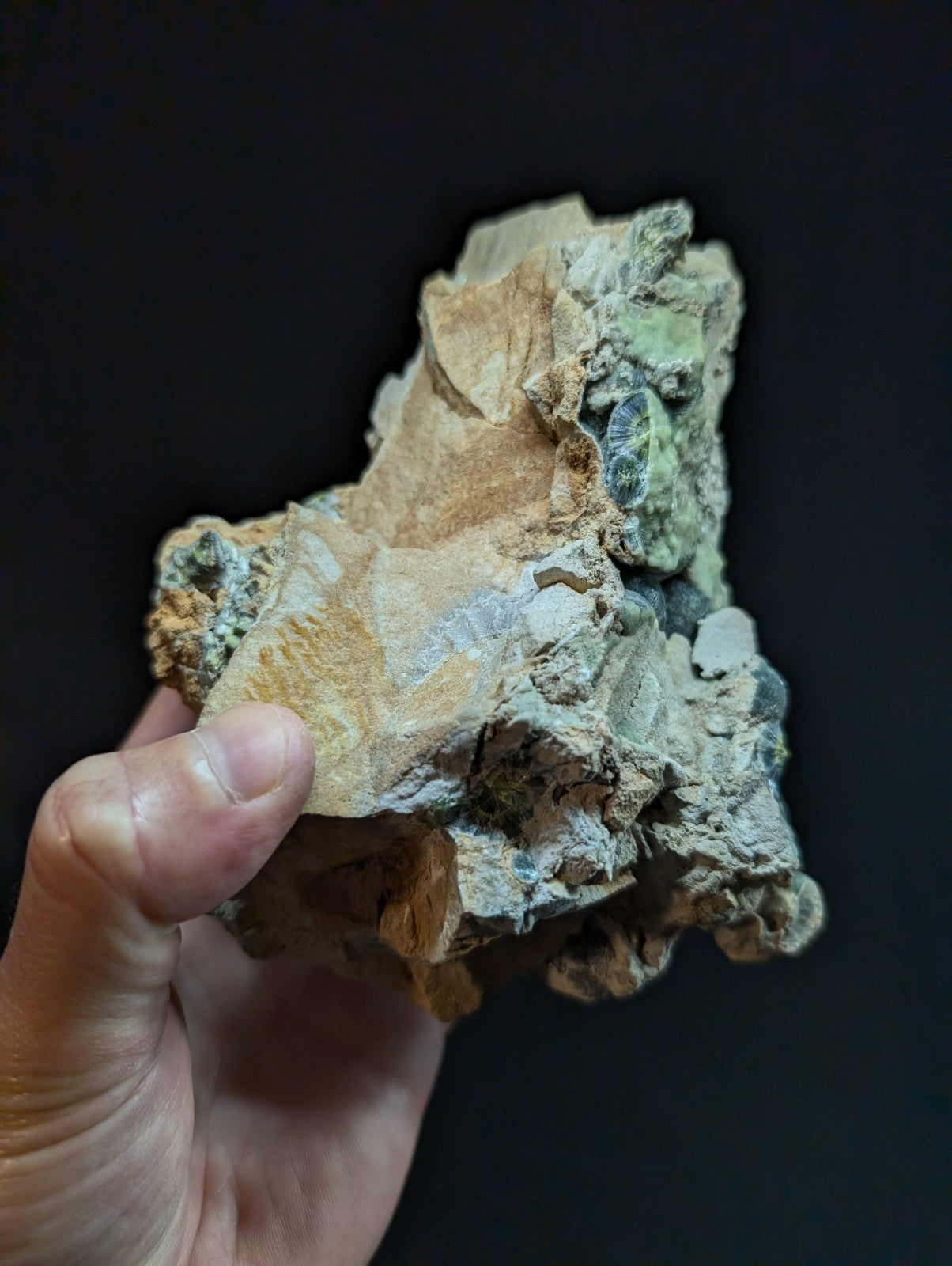 A rugged, irregularly shaped mineral specimen with patches of earthy tan and vibrant greenish-blue hues.