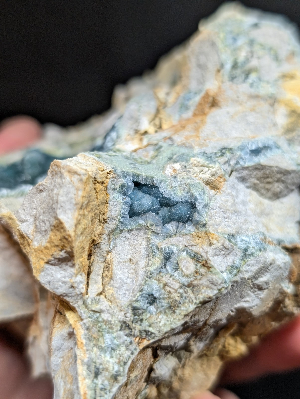 A rugged, naturally occurring mineral specimen featuring a striking blue crystalline formation nestled within a matrix of gray and yellowish rock.