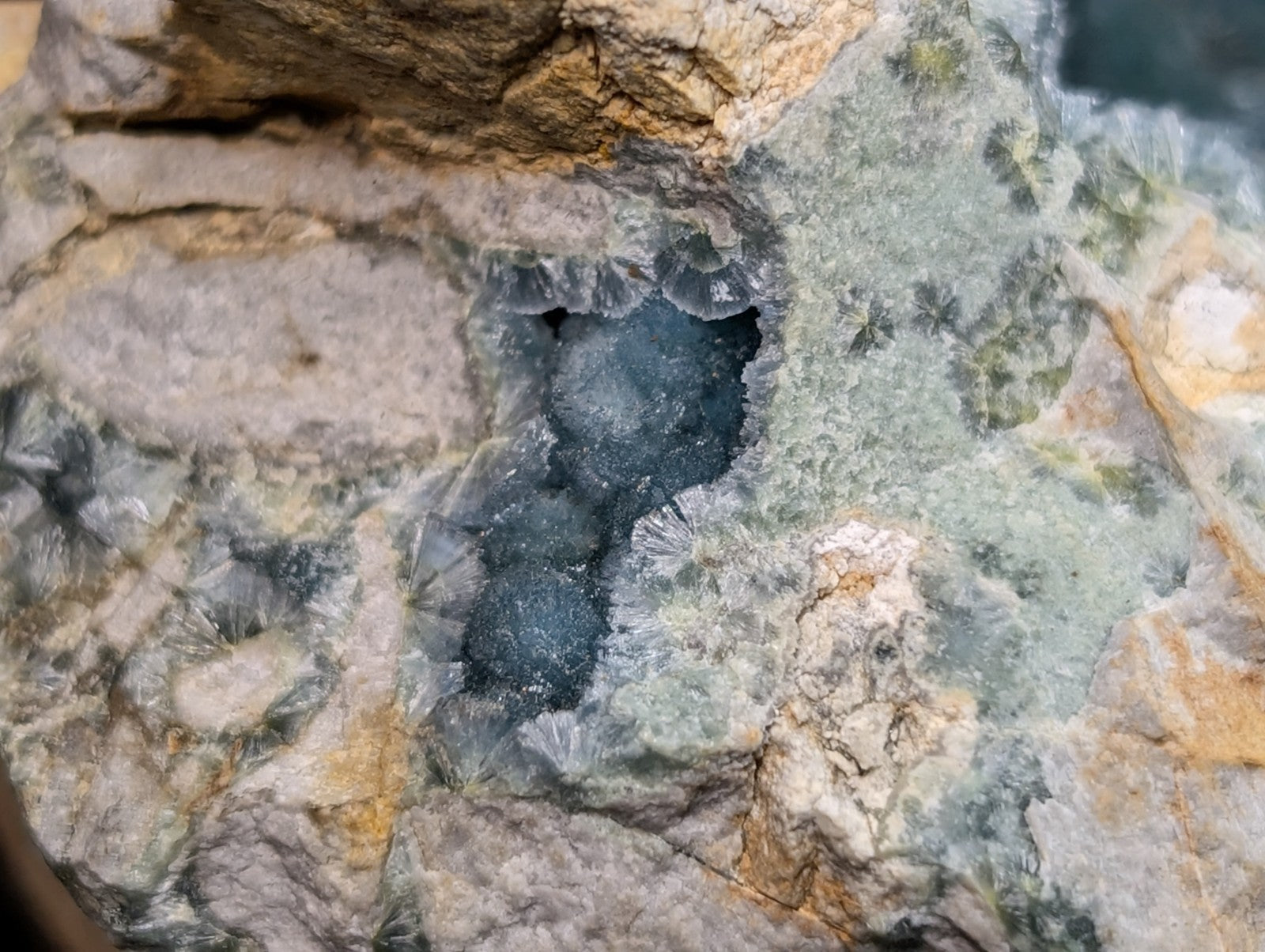 A striking blue druzy quartz geode nestled within a rugged, earthy rock matrix.