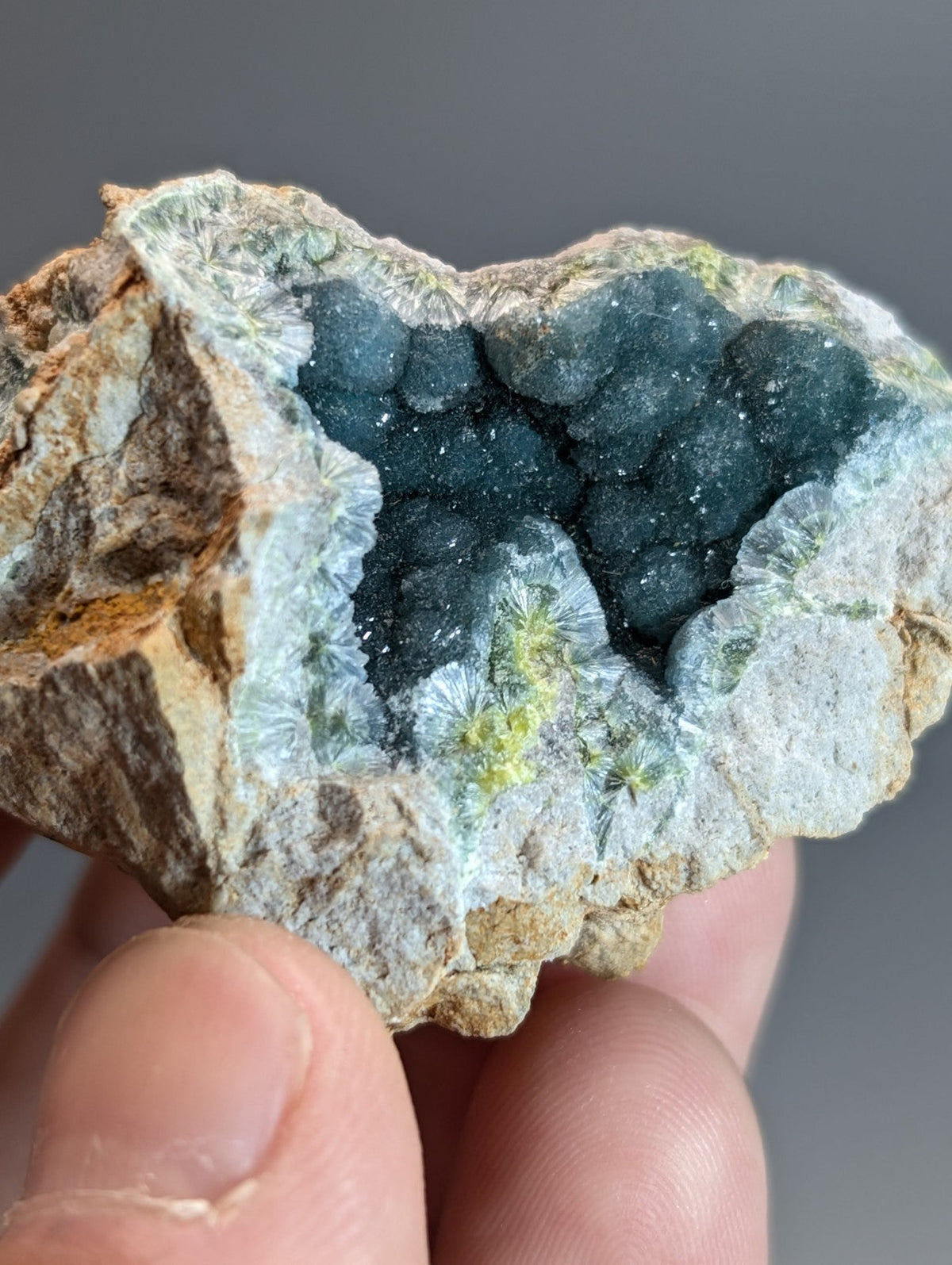 A hand holds a rare blue and green wavellite geode with dark blue-green druzy crystals from Garland County Arkansas