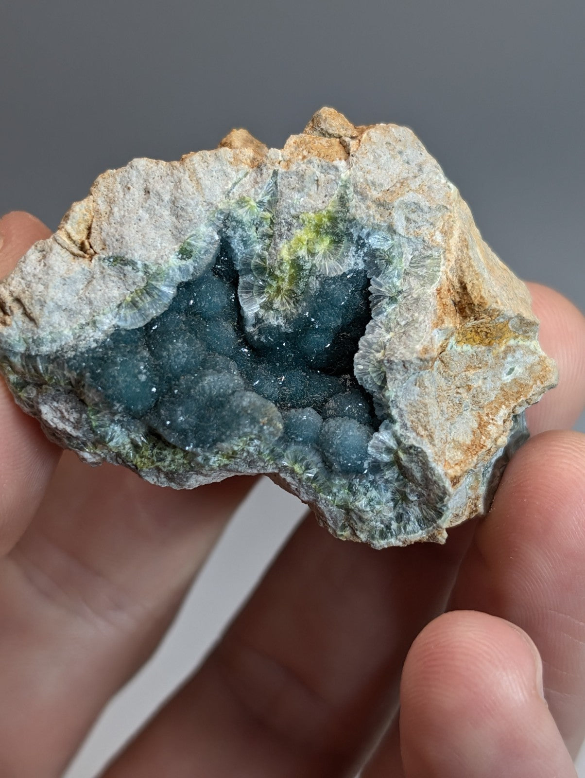 A hand holding a rare blue and green wavellite geode with deep blue druzy crystals from Garland County Arkansas